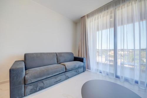 a living room with a couch and a large window at Mayfair by Premier Suites MT in Is-Swieqi