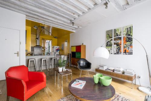 un salon avec une chaise rouge et une table dans l'établissement Veeve - Bright Beams, à Paris