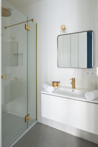 une salle de bain avec un lavabo et une douche en verre dans l'établissement Veeve - Bright Beams, à Paris