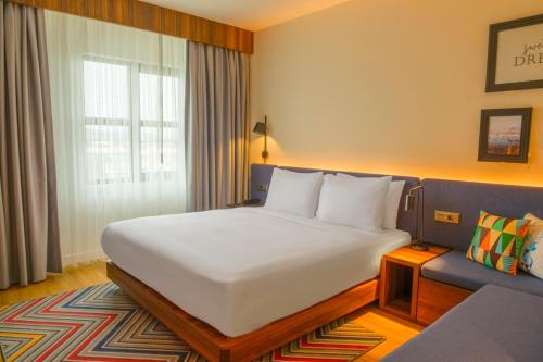 a bedroom with a large white bed and a couch at Hampton By Hilton Sakarya in Sakarya