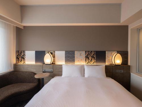 um quarto de hotel com uma cama e uma cadeira em insomnia KYOTO OIKE em Quioto