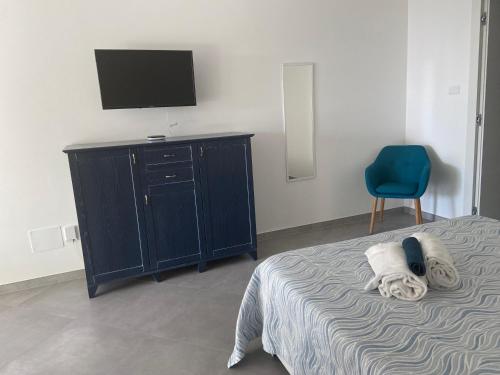 een slaapkamer met een bed en een tv en een blauwe stoel bij L'angolo di Anna in Noli