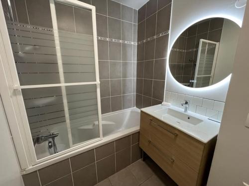La salle de bains est pourvue d'une baignoire, d'un lavabo et d'un miroir. dans l'établissement Dahlia YourHostHelper, à Caen