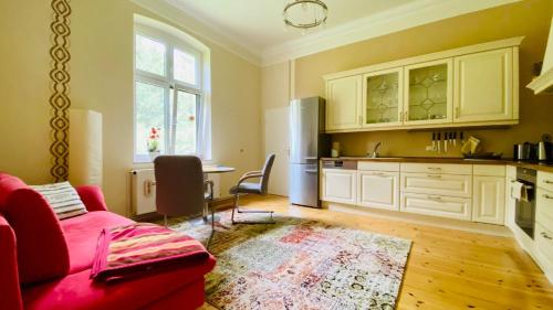 a living room with a red couch and a kitchen at Ferienwohnung Villa am Haussee in Feldberg