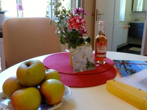 una mesa con manzanas y una botella de vino y flores en Ferienwohnung Villa am Haussee, en Feldberg