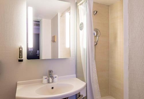 a white bathroom with a sink and a shower at B&B HOTEL Bordeaux Sud in Villenave-dʼOrnon