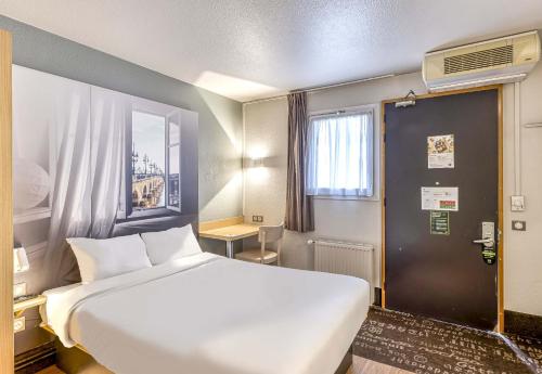 een slaapkamer met een groot wit bed en een raam bij B&B HOTEL Bordeaux Sud in Villenave-dʼOrnon