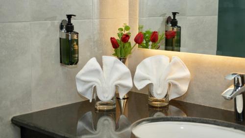 KYRIAD HOTEL SALALAH في صلالة: بالوعة الحمام مع وجود منشفتين بيضاء على منضدة