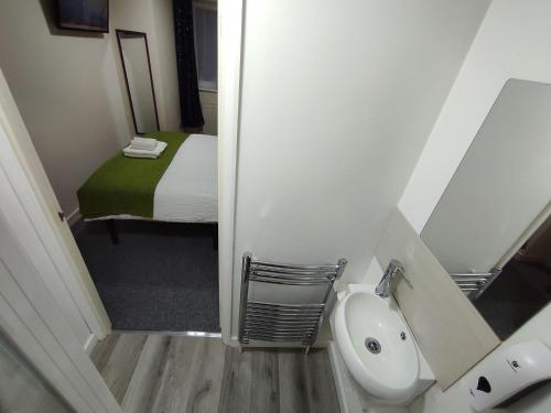 a small bathroom with a sink and a bed at Osney Juniper Studio - Self Contained Studio Flat in Oxford