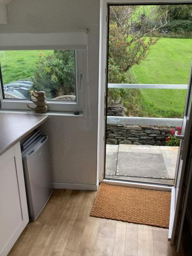 a kitchen with an open door with a view of a yard at Awel Y Mor - cosy apartment. in Verwick