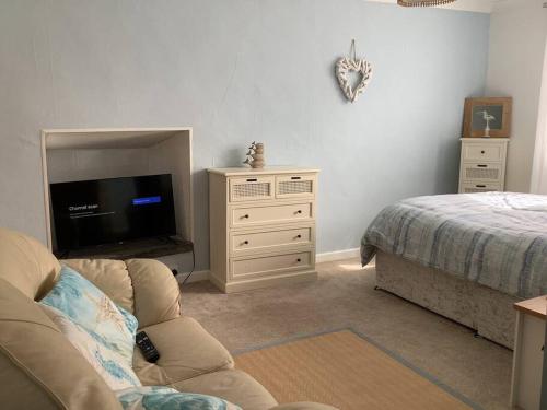 a living room with a couch and a tv and a bed at Awel Y Mor - cosy apartment. in Verwick