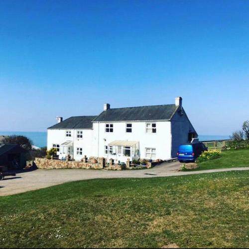 a white house with a blue car parked in front of it at Awel Y Mor - cosy apartment. in Verwick