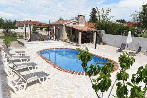 a swimming pool with chairs and a house at Villa Palace in Donji Zemunik