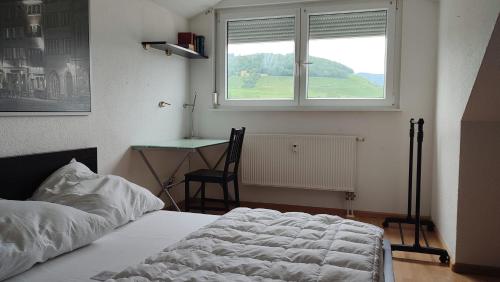 1 dormitorio con cama, escritorio y ventana en Haus Castellblick 3, en Ballrechten