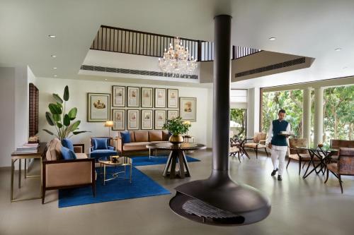 a person walking through a living room with a fireplace at Anand Kashi by the Ganges Rishikesh - IHCL Seleqtions in Rishīkesh