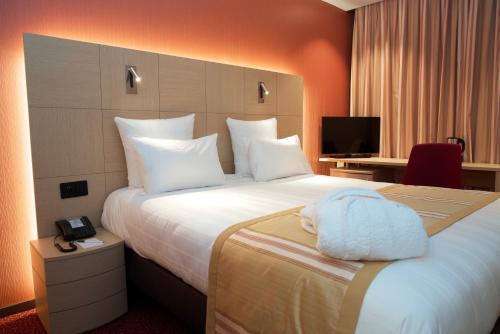 Una habitación de hotel con una cama con una toalla. en Nash Airport Hotel en Ginebra