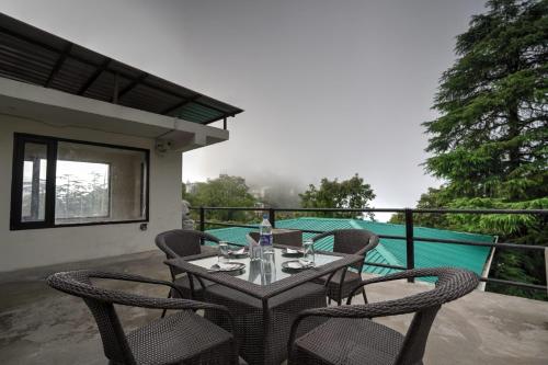 a table and chairs on the balcony of a house at Hotel Lodge Hill Near Mall Road, Mussoorie in Mussoorie