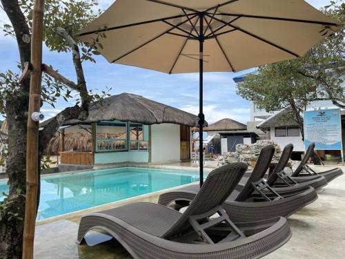 eine Gruppe von Stühlen und einem Sonnenschirm neben einem Pool in der Unterkunft Lopez Beach Resort in Sipalay