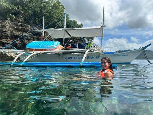 a woman in the water in front of a boat at Lopez Beach Resort in Sipalay