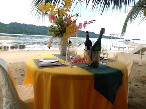 a table with wine bottles and glasses on a beach at Lopez Beach Resort in Sipalay