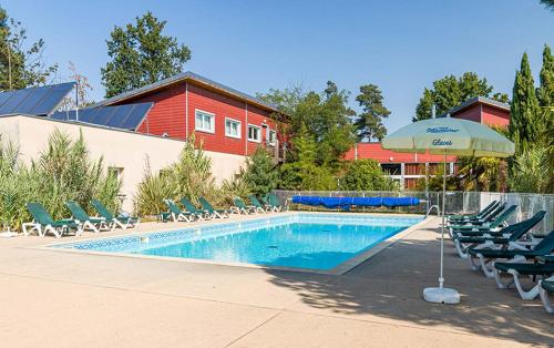 ein Swimmingpool mit Stühlen und einem Sonnenschirm in der Unterkunft Détendez-vous à Richelieu in Chaveignes
