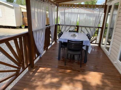a wooden deck with a table and chairs on it at Mobilhome Vias plage dans Camping in Vias