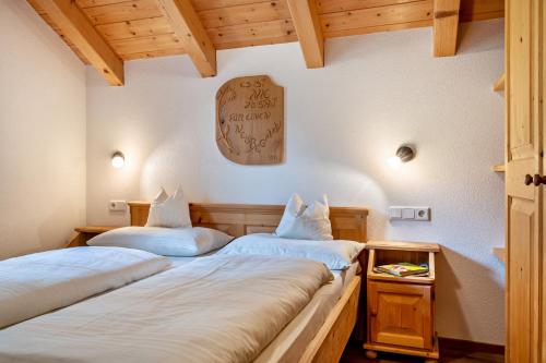 two beds in a room with wooden ceilings at Kranebitterhof Apt Enzian in Valdaora