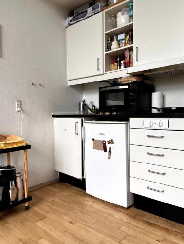 cocina con armarios blancos y nevera blanca en The room in Rødovre for a couple or women en Rødovre