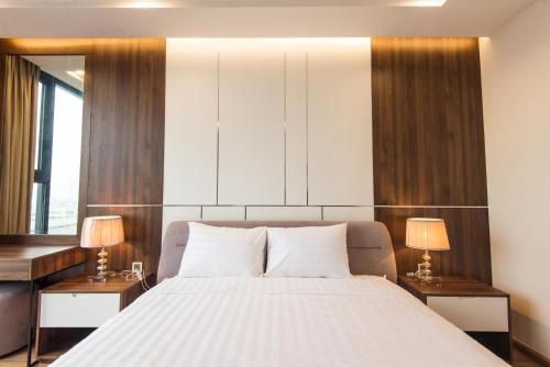 a bedroom with a large white bed with two lamps at Vinhomes Metropolis luxury Hotel & Residence in Hanoi