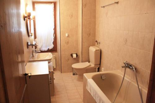 a bathroom with a tub and a toilet and a sink at La Petite Auberge in Versegeres 
