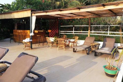 acovered patio with chairs and tables and a table at Villa 'The Blue House' - Qbungalows in Kep