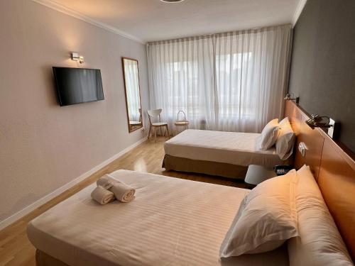 a hotel room with two beds and a flat screen tv at AP Hotel Madrid Airport in Madrid