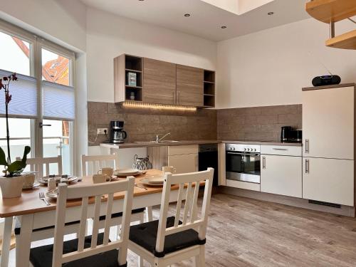 eine Küche mit einem Tisch und Stühlen sowie eine Küche mit weißen Schränken in der Unterkunft Ferienwohnungen Am Kaufmannshof in Quedlinburg