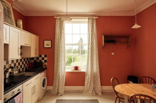 une cuisine avec une table, une fenêtre et une table dans l'établissement Thirsk Hall South Wing, North Yorkshire, à Thirsk