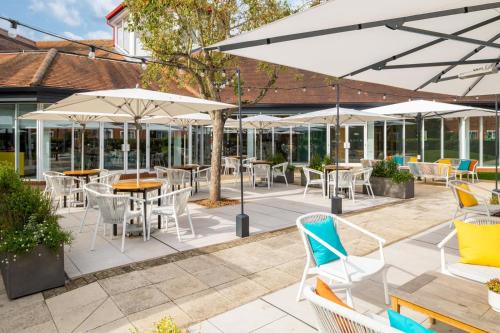 a patio with tables and chairs and umbrellas at Holiday Inn Aylesbury, an IHG Hotel in Aylesbury