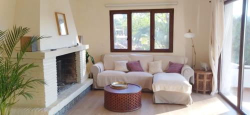 a living room with a couch and a fireplace at Bonita casa blanca en el bosque. in Córdoba