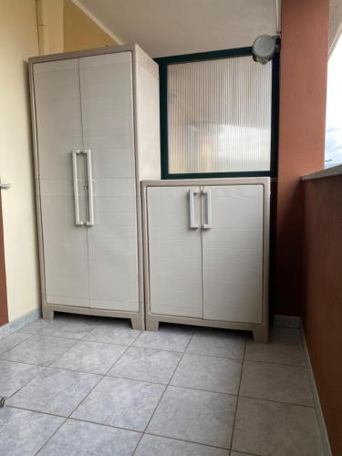 two white cabinets in a room with a tile floor at Da Gin in Bosa Marina