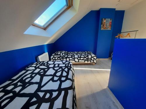 2 camas en una habitación con paredes azules en Maison de charme à Rouen Max 10 personnes en Rouen