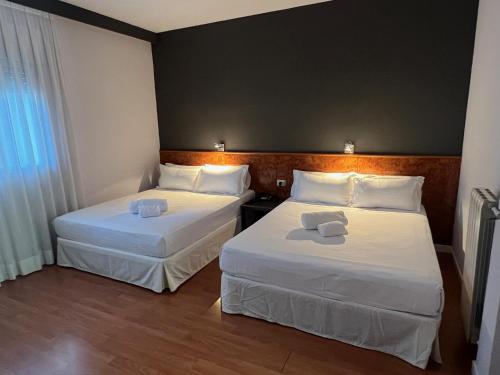 AP Hotel Madrid Airport في مدريد: سريرين في غرفة الفندق ذات شراشف بيضاء