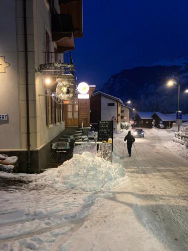 a person walking down a snow covered street at night at La Petite Auberge in Versegeres 