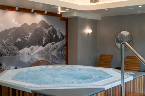 a jacuzzi tub in a room with a mountain mural at RentPlanet - Apartamenty Zakopiańskie in Zakopane