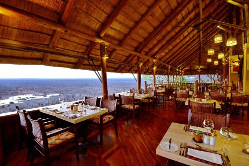 a restaurant with tables and chairs and a view at Victoria Falls Safari Lodge in Victoria Falls