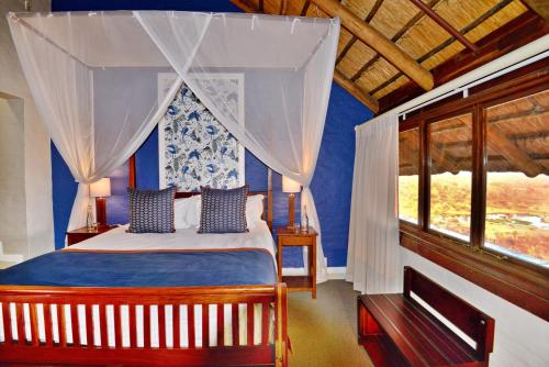 a bedroom with a bed with blue walls and a window at Victoria Falls Safari Lodge in Victoria Falls