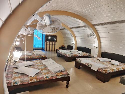 a room with three beds and an arched window at Hotel Rangoli in Jaipur