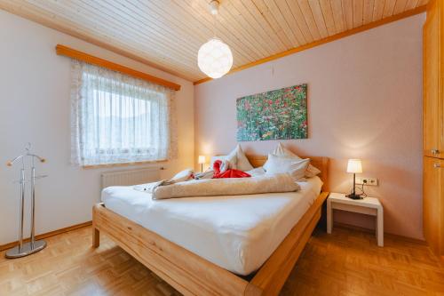 a bedroom with a large bed with white sheets at Kamenhof in Weissensee