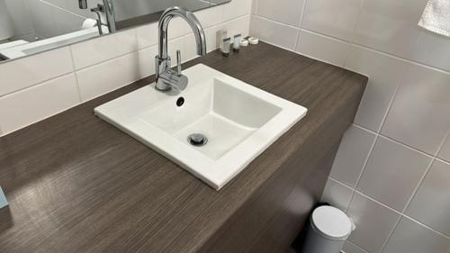 La salle de bains est pourvue d'un lavabo blanc et d'un miroir. dans l'établissement Townsville City Motel, à Townsville