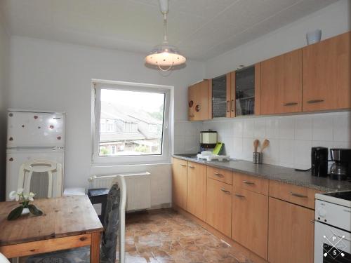 eine Küche mit Holzschränken, einem Tisch und einem Fenster in der Unterkunft Wohnung nähe Daimler 1 OG in Bremen