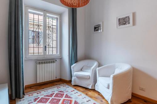 a room with two white chairs and a window at Trastevere Delightful Apartment in Rome