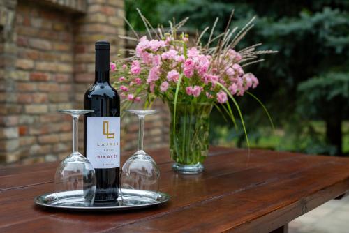 two bottles of wine and a vase of flowers on a table at Dégi Festetics-kastély, Park Vendégház in Dég