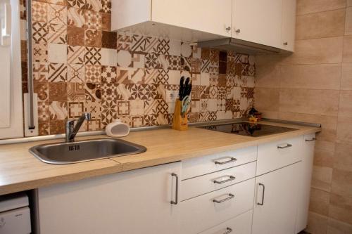 una cocina con armarios blancos y fregadero en Casa Llurgo, en Deltebre